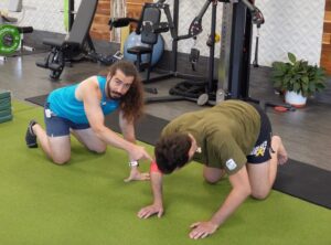 Rene on the floor on his hands and knees. 
 With a little pressure he is bending and straightening his elbows ( the right elbow is wrapped with red muscle floss). 